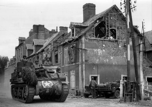 M7B1 Priest of the 14th Armored Field Battalion, 2nd Armored Division driving down Rue Holgate, Carentan, 18 June 1944.jpg